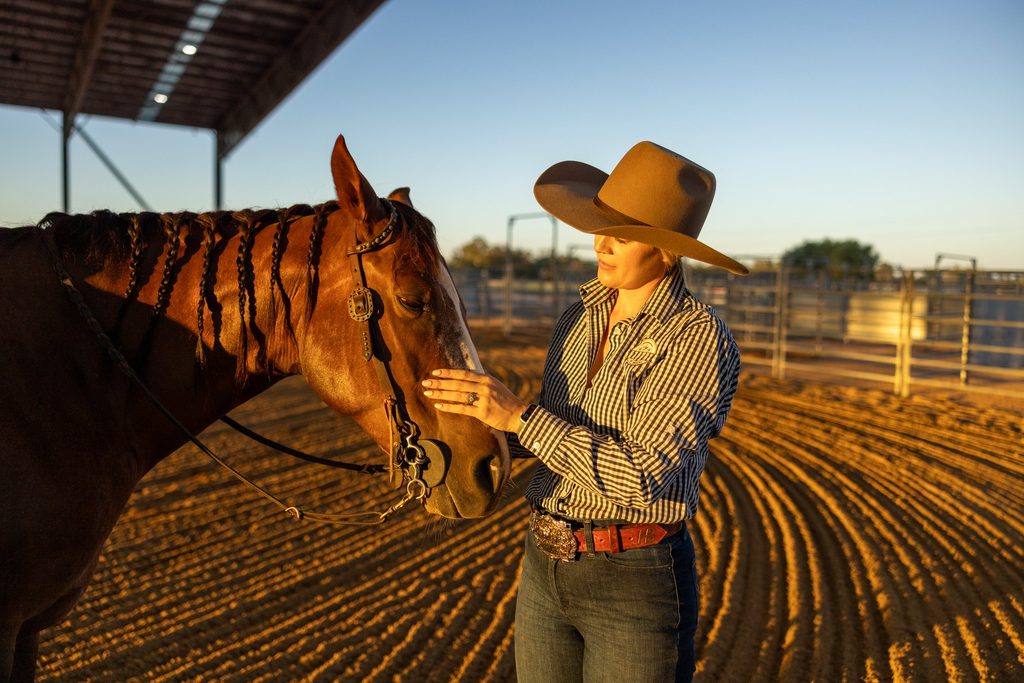 Woman standing beside a horse in warm afternoon light