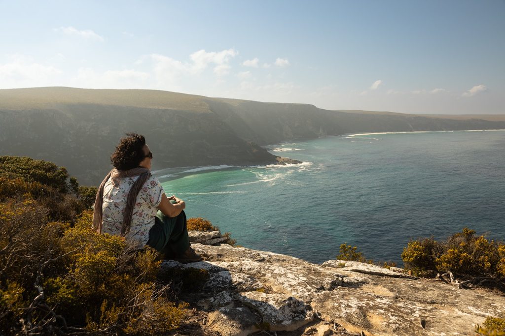 Person overlooking a coastal bay from a cliff