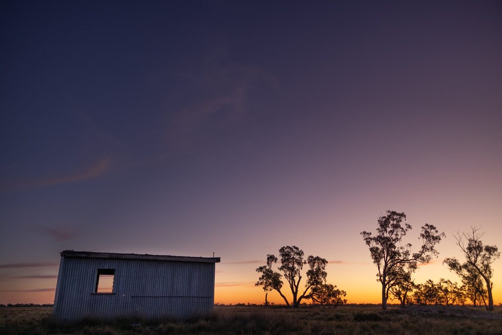 Farm shed silhouetted against a purple twilight sky